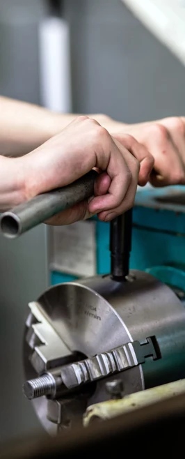 Close-up of a student’s hands tightening the chuck of a lathe machine with a metal tool in a mechanical engineering workshop. Close-up of a student’s hands tightening the chuck of a lathe machine with a metal tool in a mechanical engineering workshop.